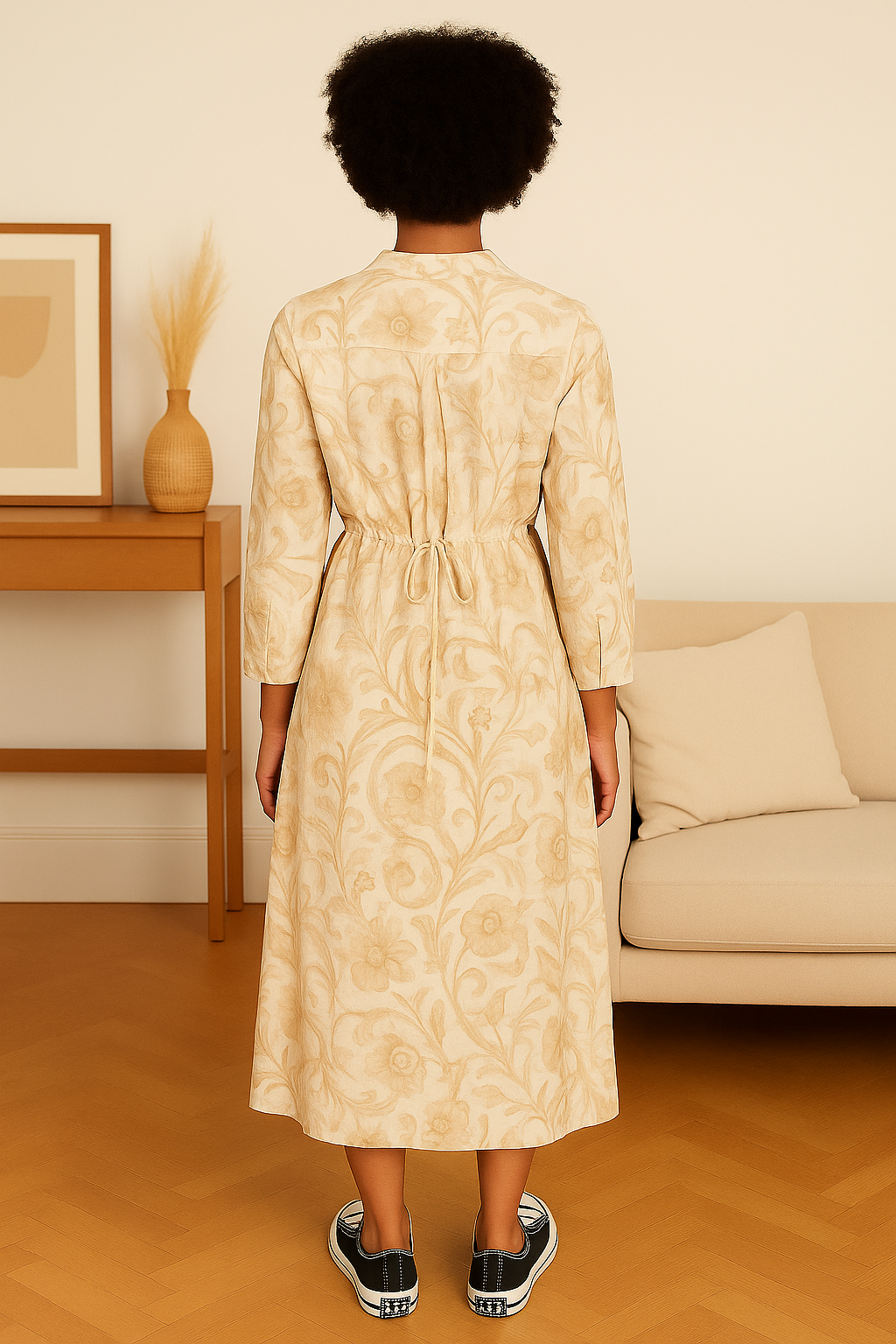back view of woman wearing beige floral Italian maxi dress with long sleeves and tie waist in modern living room