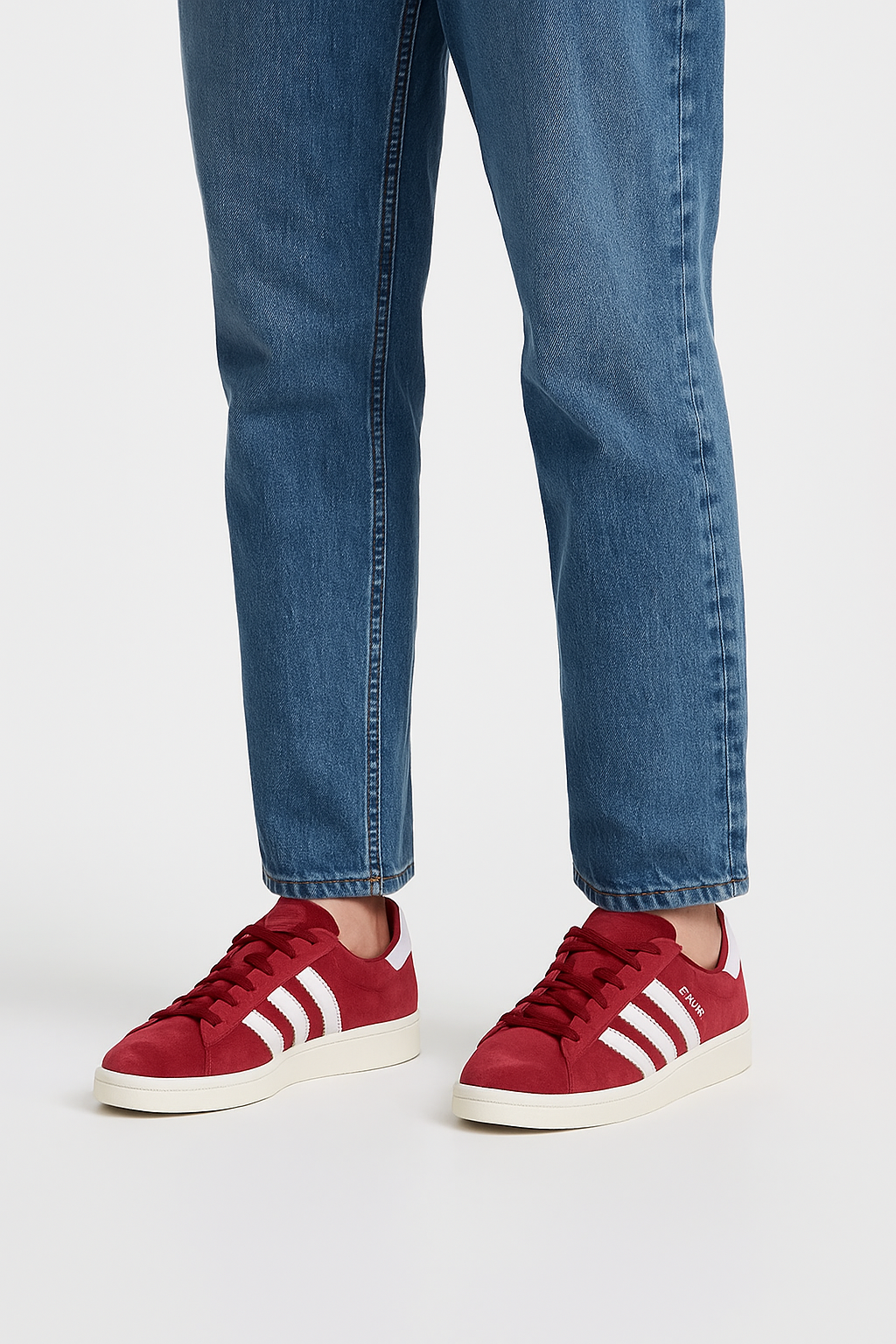 Red Adidas Campus 80s shoes with white 3-Stripes, nubuck upper, and rubber sole worn with blue jeans