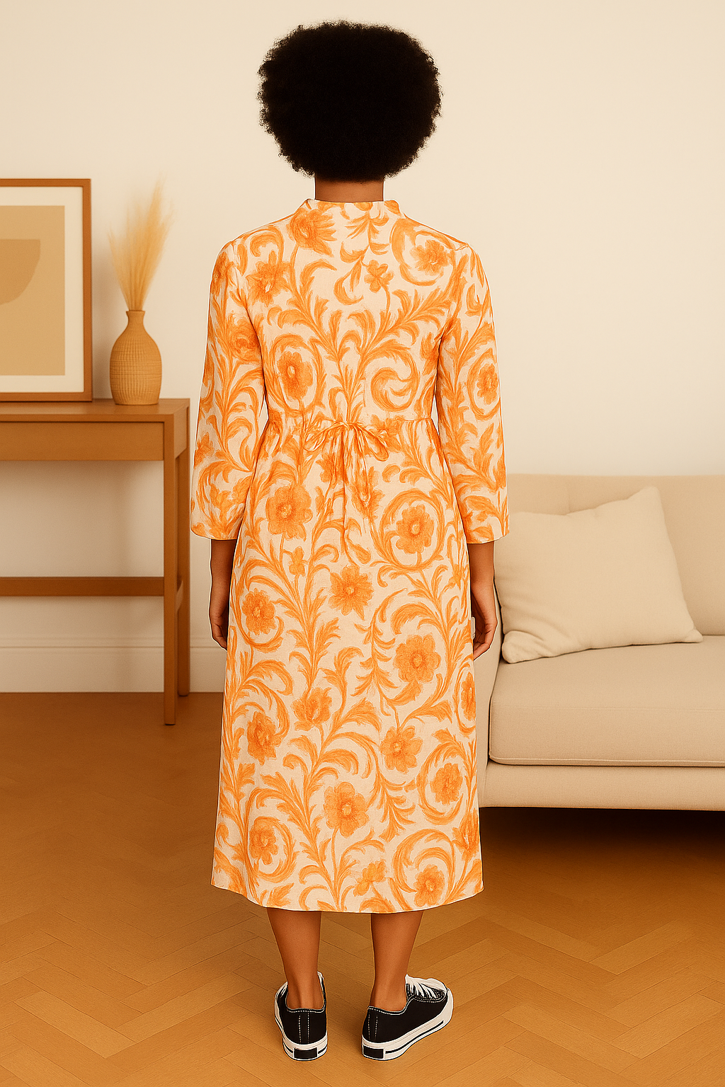 Back view of woman wearing an orange floral Italian Maxi Dress made of lightweight viscose in a casual living room setting