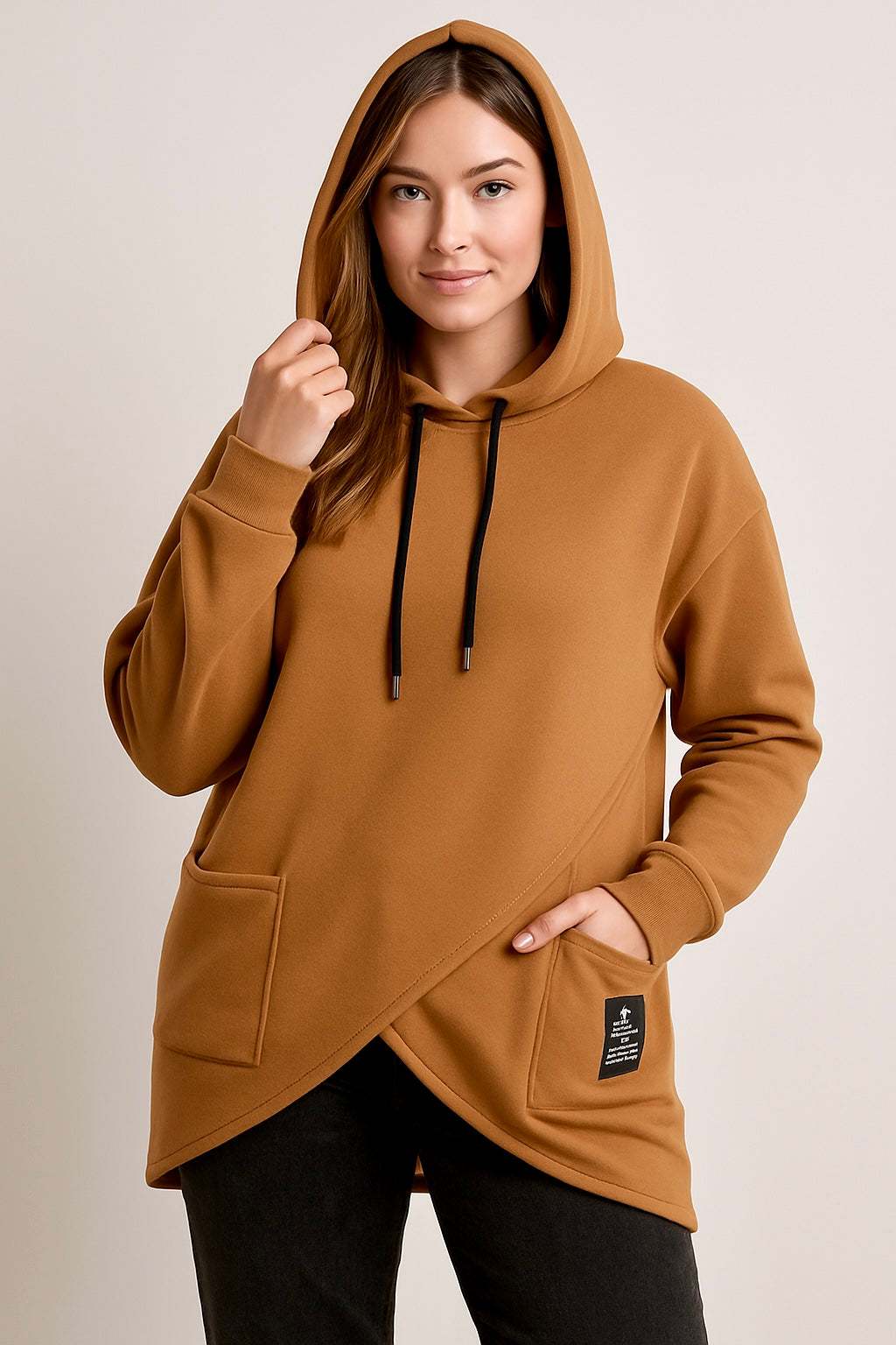 Woman wearing a brown suede feel hoodie with pockets and black drawstrings, styled with black pants