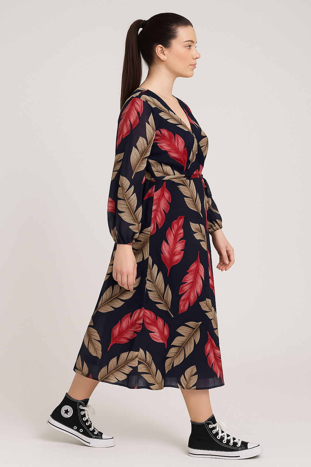 Woman wearing Jess Floral Wrap Dress with navy base and red and beige leaf pattern, paired with black high-top sneakers, side view