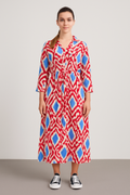 Woman wearing a red and blue patterned Italian Collar Button Maxi Dress with long sleeves and a collar, styled casually with black sneakers.