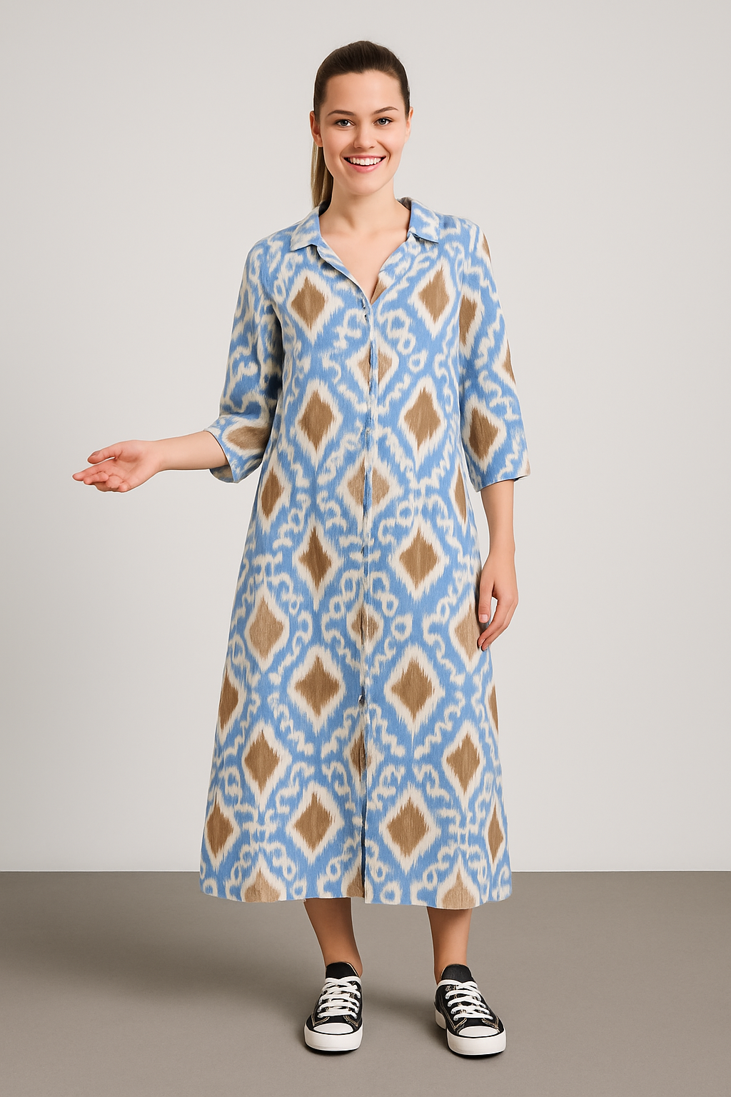 Woman wearing a blue and beige patterned Italian collar button maxi dress with three-quarter sleeves and black sneakers against a neutral background