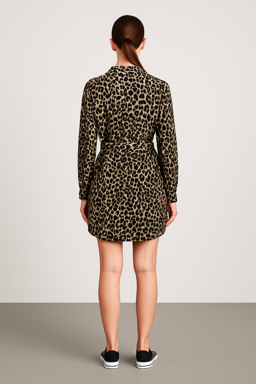 Rear view of woman wearing leopard print belted long-sleeve dress with collared neckline and black sneakers