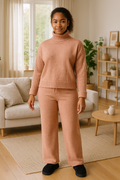 woman wearing soft knitted co-ord set with turtleneck sweater and relaxed trousers in cozy living room